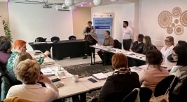 Uczestnicy szkolenia siedzą wokół stołu w przestronnej sali spotkań.