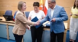 Mężczyzna i kobieta uściski dłoni przed stołem, symbolizując powołanie do składu gremium