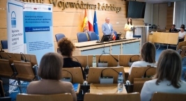 Osoby zgromadzone przed podium, skupione na wystąpieniu mówcy.