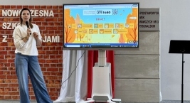 Stojąca kobieta przed dużym ekranem, który wyświetla różne dane lub obrazy