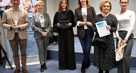 Grupa przedstawicieli RCPS i uczestnik wydarzenia z certyfikatem oraz torbą z nagrodami.