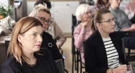 Zespół ludzi siedzi na krzesłach, angażując się w rozmowę w relaksującej scenerii